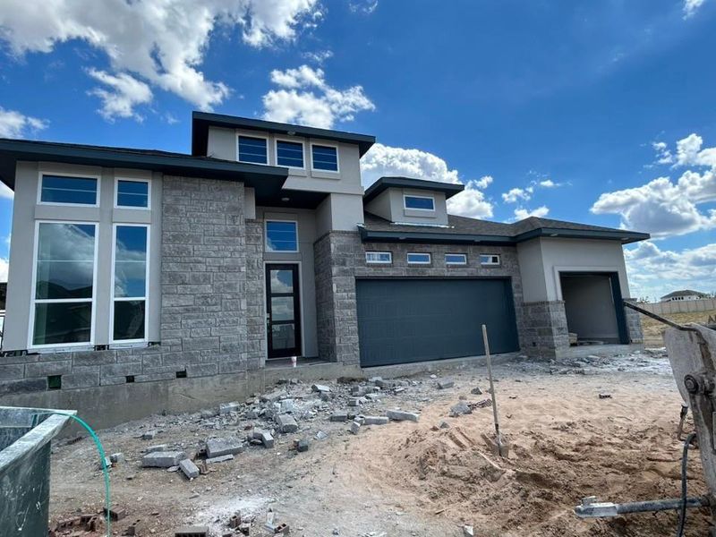 Prairie-style house with stone siding and a garage