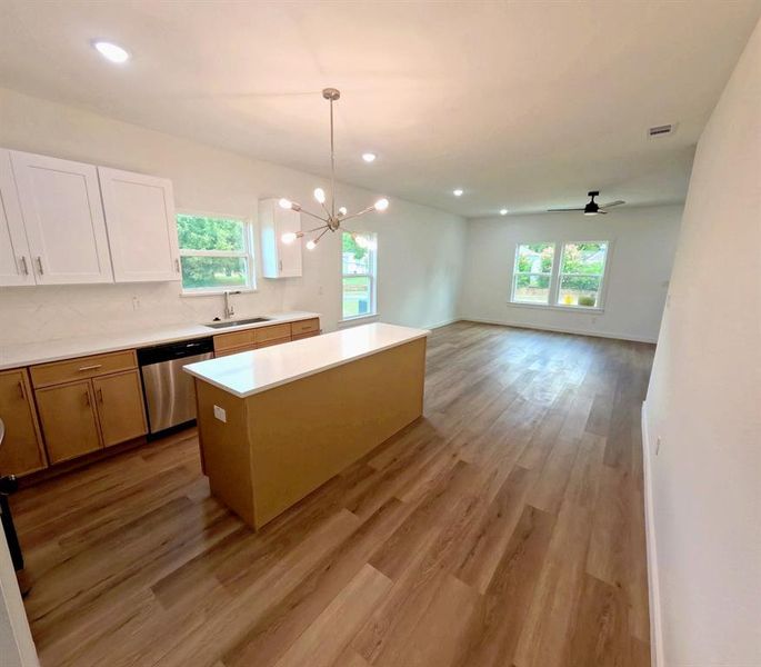 Kitchen with pendant lighting, a kitchen island, a chandelier, decorative backsplash, and stainless steel dishwasher Kitchen with pendant lighting, a kitchen island, a chandelier, decorative backsplash, and stainless steel dishwasher