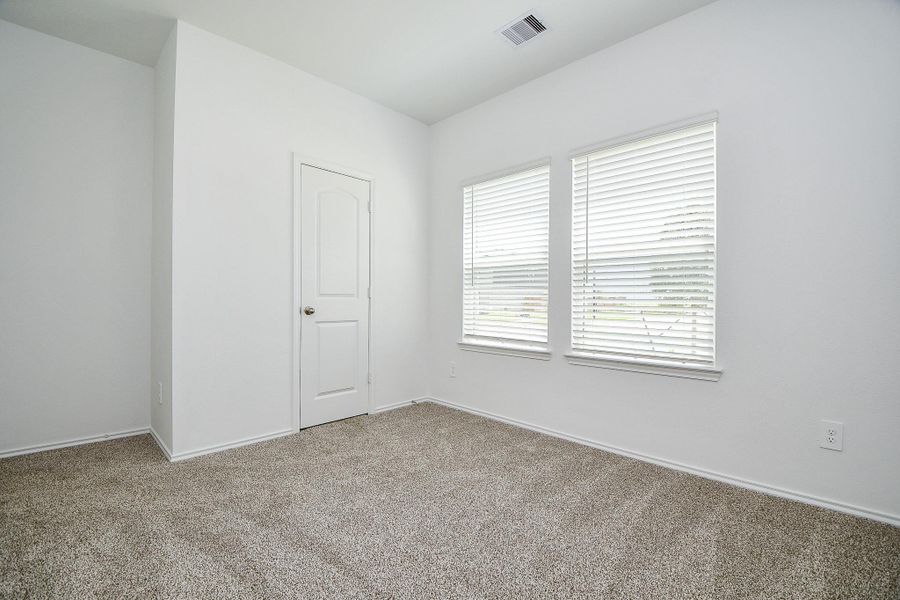 Cozy downstairs second bedroom with ample natural light and plush carpet.
