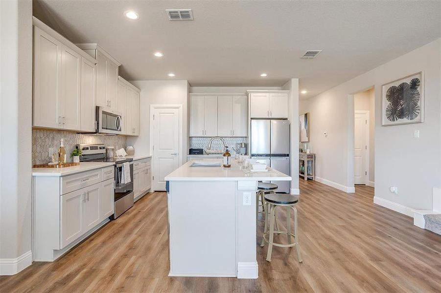 Kitchen featuring light wood-type flooring, white cabinetry, and appliances with stainless steel finishes