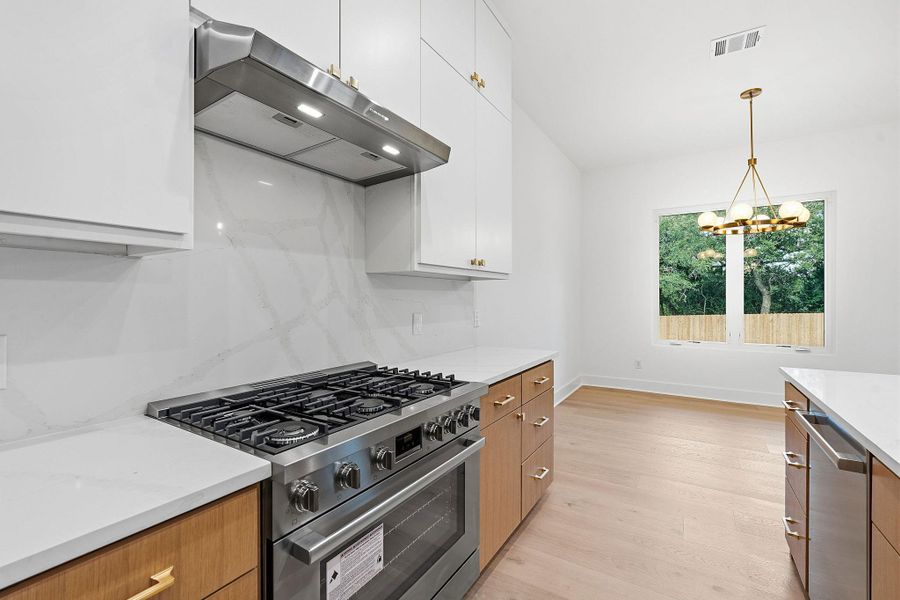 Smooth stone countertops pair perfectly with warm wood floors in this modern culinary space.