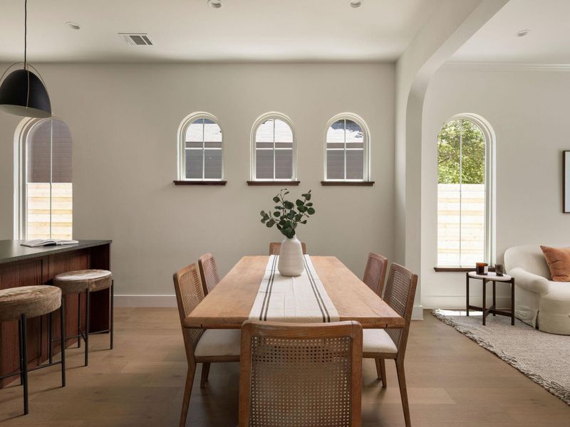 Elegant arched windows frame a bright dining area, seamlessly connecting to an open-concept living space.