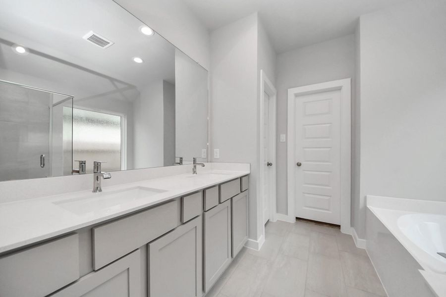 Indulge in a spa-like retreat within the confines of this primary bathroom. Delight in a spacious walk-in shower enveloped in stylish tile surround, unwind in a separate garden tub adorned with custom detailing.