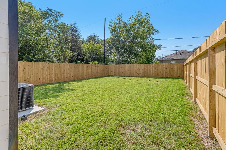 Private backyard view from the back door featuring a fully fenced yard with fresh green space—perfect for outdoor gatherings, pets, or relaxing in your own private retreat.