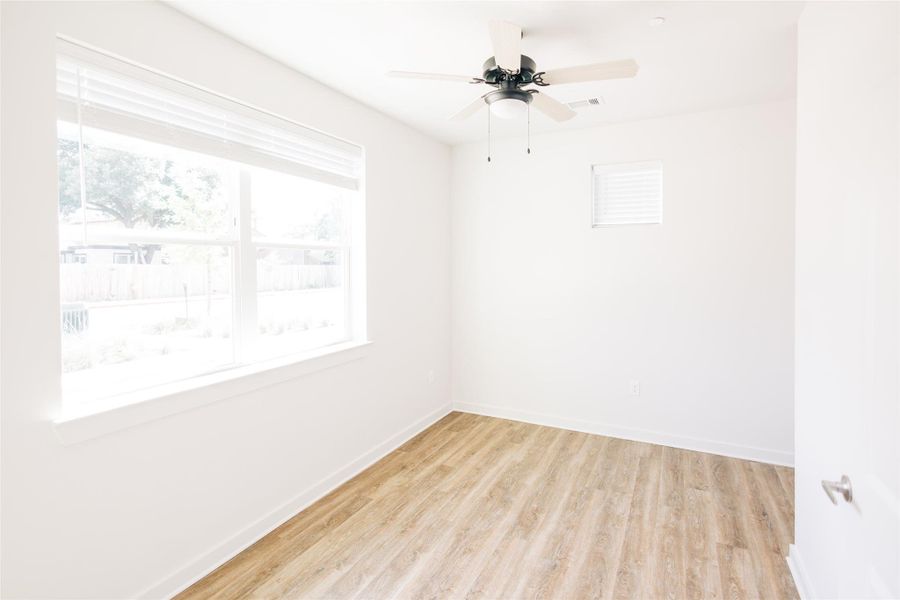 Empty room featuring light wood-style floors, baseboards, and ceiling fan