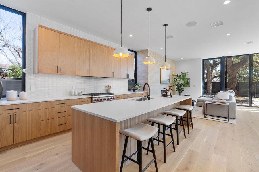 Euro-style white oak cabinetry is complimented by a light textural backsplash and Quartz countertops including the massive 10’ island with plenty of additional cabinet storage