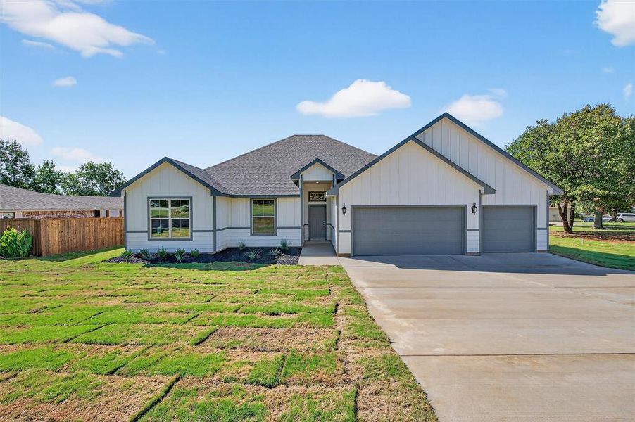 Modern inspired farmhouse with a garage, driveway, and roof with shingles
