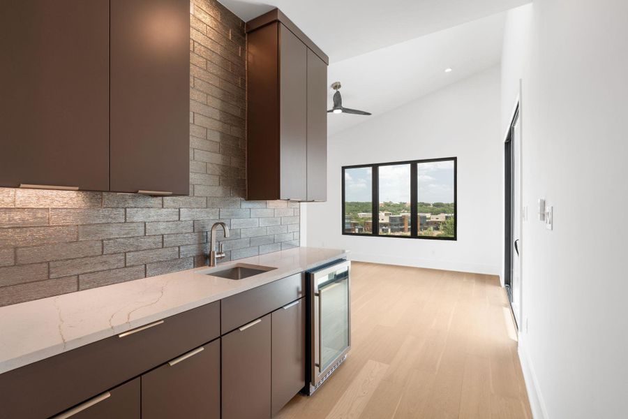 A refined wet bar, complemented by sleek cabinetry, hard flooring, and a picturesque outdoor view.