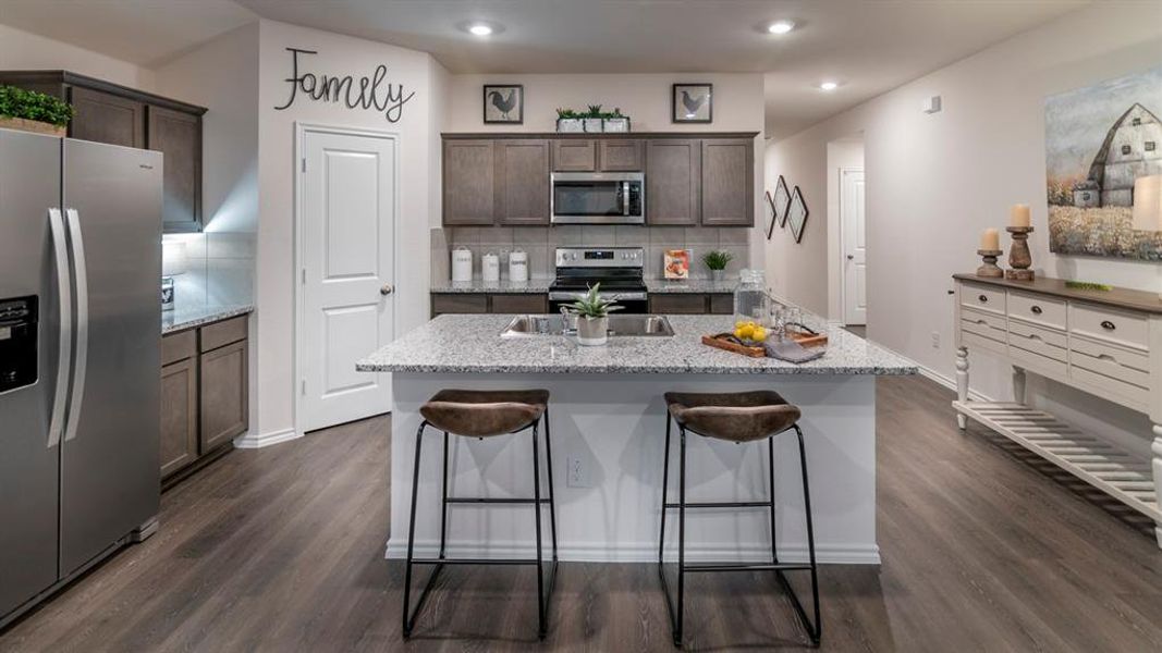 Kitchen with stainless steel appliances, dark wood finish cabinets, backsplash, light stone counters, and recessed lighting