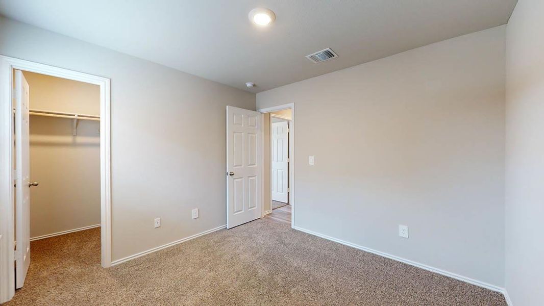 Unfurnished bedroom with a walk in closet and light colored carpet