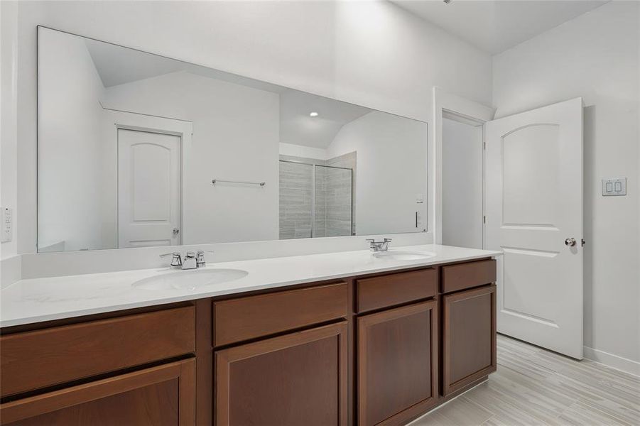 Bathroom featuring a shower stall, double vanity, and light wood finished floors