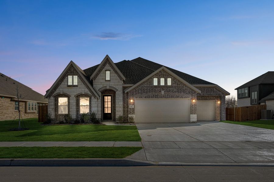 Single-story home with brick and stone exterior, two-car garage, and concrete driveway at dusk