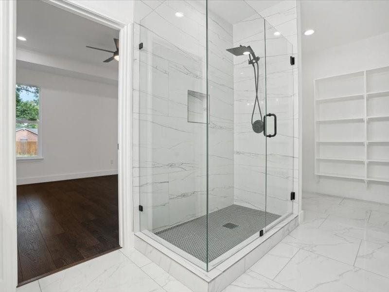 Bathroom with a shower with shower door, ceiling fan, built in shelves, and tile patterned floors