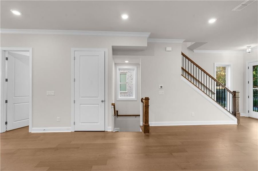 Unfurnished living room featuring crown molding, stairs, wood finished floors, and recessed lighting