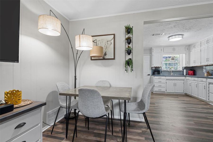 Dining space with dark wood-type flooring and crown molding Dining space with dark wood-type flooring and crown molding