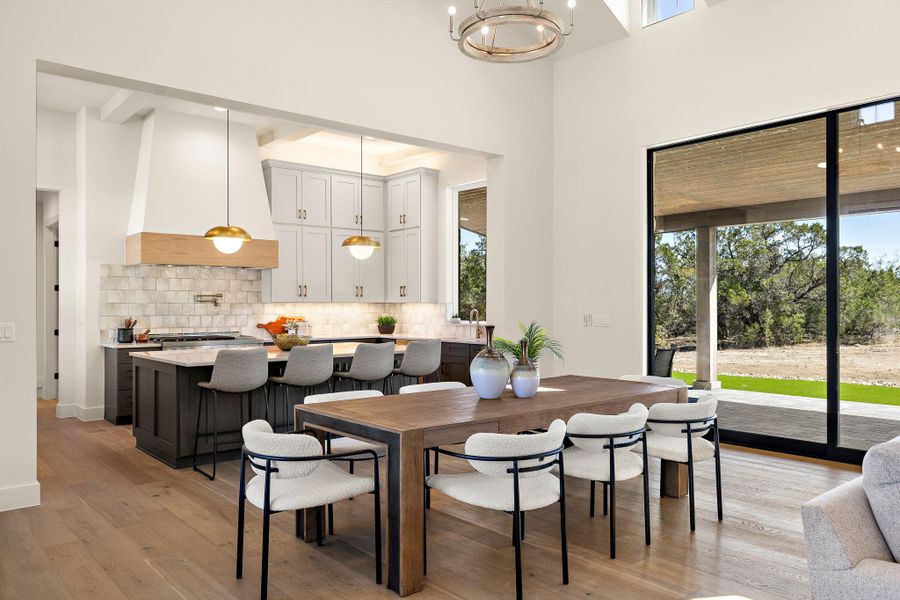 Dining space featuring light wood finished floors, a high ceiling, and a wealth of natural light