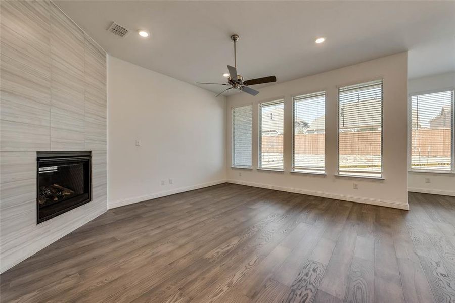 Unfurnished living room featuring ceiling fan, dark hardwood / wood-style flooring, a fireplace, and a wealth of natural light