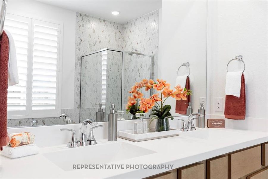 Full bath with a marble finish shower and double vanity