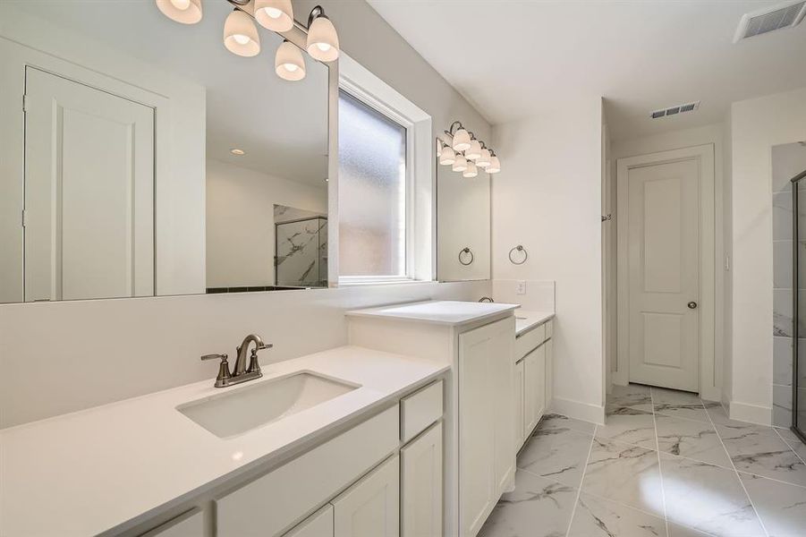 Bathroom with an enclosed shower, visible vents, marble finish floor, and a sink