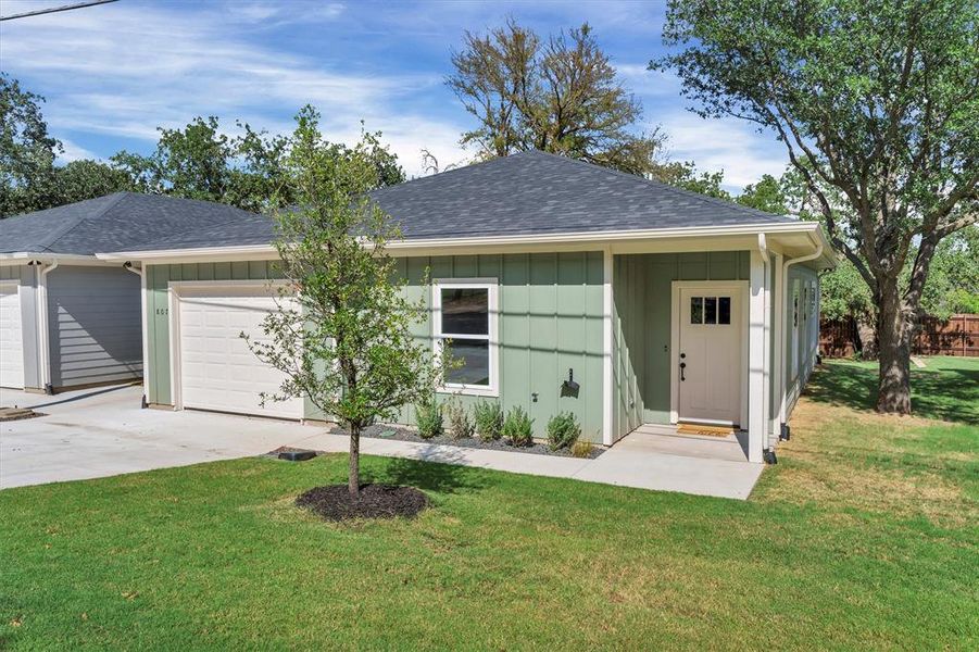 Ranch-style home with a shingled roof, a front yard, driveway, an attached garage, and board and batten siding Ranch-style home with a shingled roof, a front yard, driveway, an attached garage, and board and batten siding
