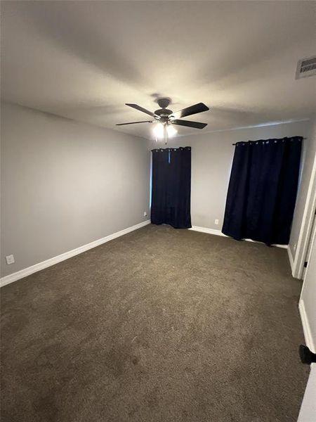 Empty room with dark colored carpet and a ceiling fan Empty room with dark colored carpet and a ceiling fan