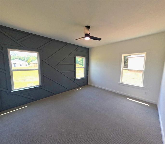 Carpeted spare room with a decorative wall and ceiling fan Carpeted spare room with a decorative wall and ceiling fan