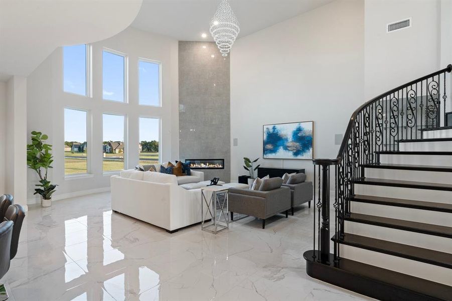 Living room with stairs, marble finish floor, a towering ceiling, and visible vents