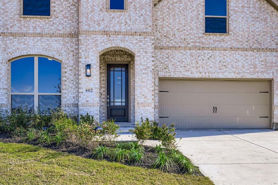 Doorway to property with concrete driveway, brick siding, and a garage Doorway to property with concrete driveway, brick siding, and a garage