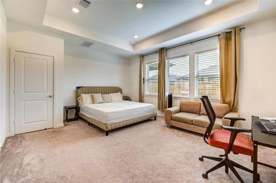 The Spacious Primary Bedroom Retreat is the ultimate sanctuary for relaxation, offering a serene ambiance with a soothing neutral palette, adorned with elegant high tray ceilings with recessed lights, and oversized windows that bathe the room in natural light framing the peaceful views of the sprawling backyard creating a calming and luxurious retreat you'll love coming home to.