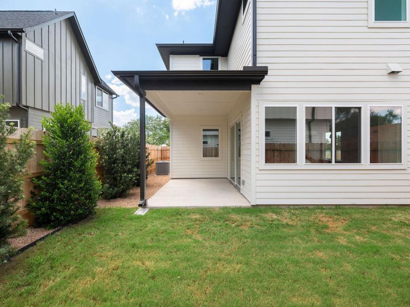 A well-maintained lawn stretches towards a covered patio and modern siding, creating a perfect outdoor retreat.