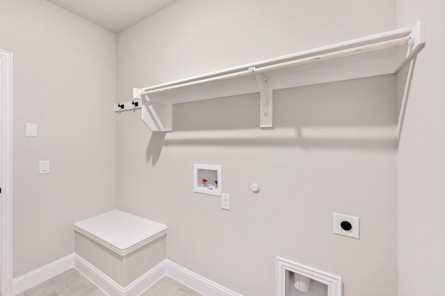 Laundry room with white wall shelf, hanging rod, washer hookups, and a small bench seat