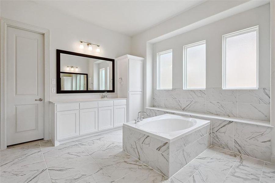 Bathroom with vanity, a bath, and light marble finish flooring