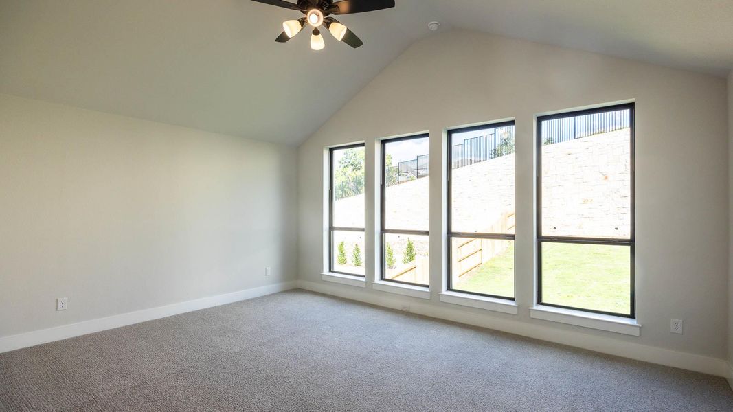 Carpeted empty room with lofted ceiling and ceiling fan