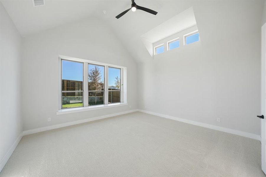 Spare room featuring high vaulted ceiling, light carpet, and a ceiling fan Spare room featuring high vaulted ceiling, light carpet, and a ceiling fan