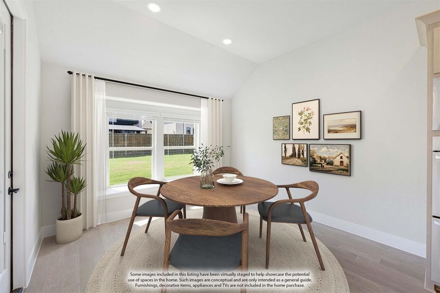 Dining area with round wood table, four chairs, large window, and gallery wall with framed artwork