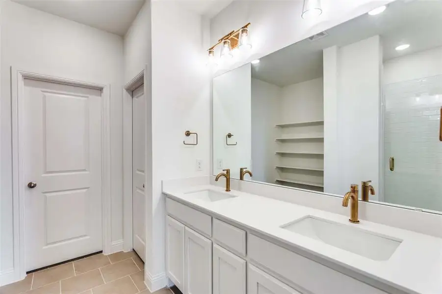 Bathroom featuring double vanity, tile patterned flooring, and a stall shower