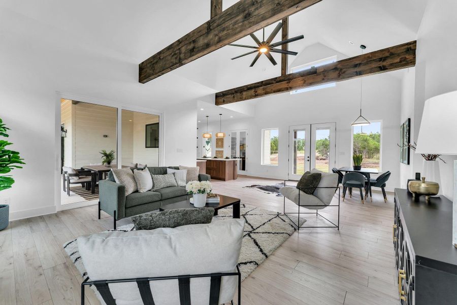 Exposed wood beams define soaring ceilings in this bright, open-concept living space with light wood flooring. Exposed wood beams define soaring ceilings in this bright, open-concept living space with light wood flooring.