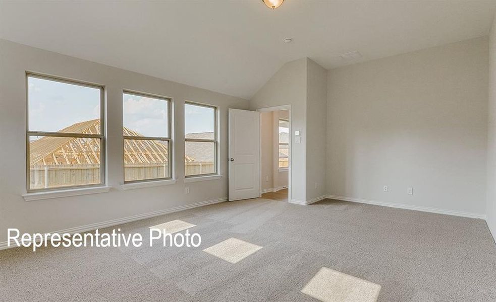 Spacious room with light gray carpeting, three large windows, a vaulted ceiling, and neutral wall paint