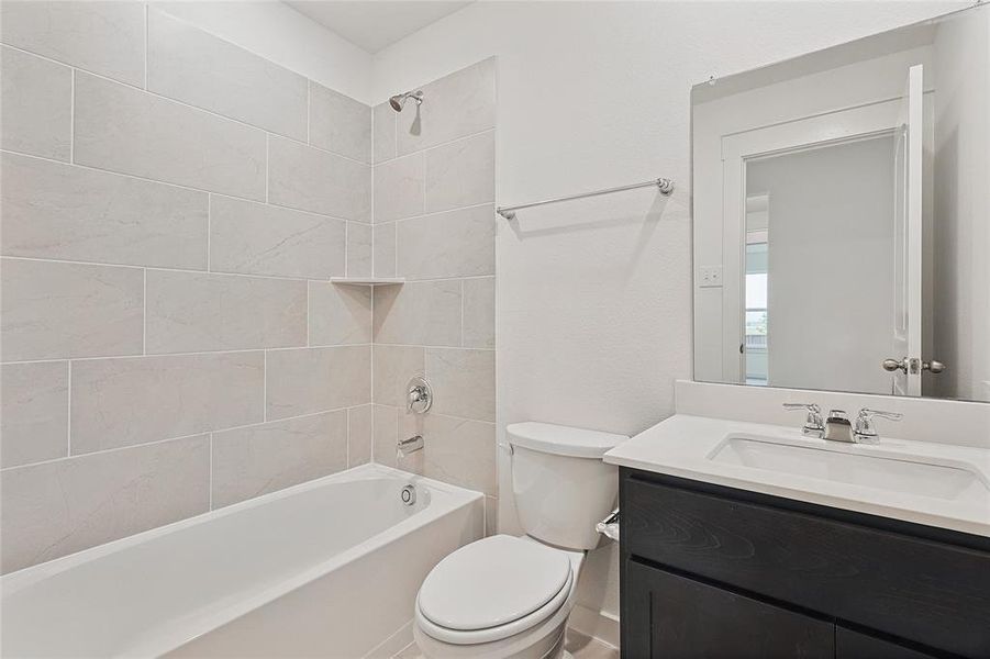 Full bathroom with toilet, tiled shower / bath, and vanity