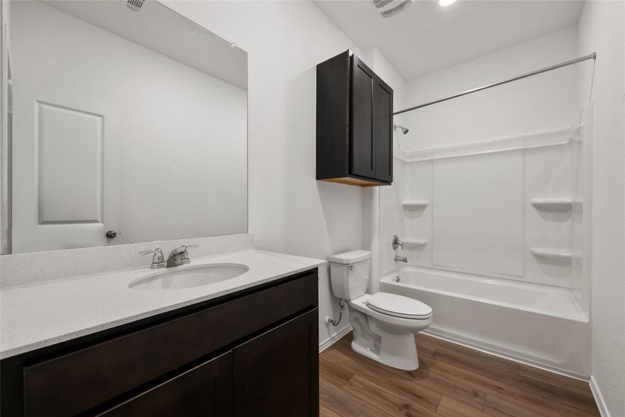 Full bath featuring wood finished floors, vanity, and tub / shower combination Full bath featuring wood finished floors, vanity, and tub / shower combination