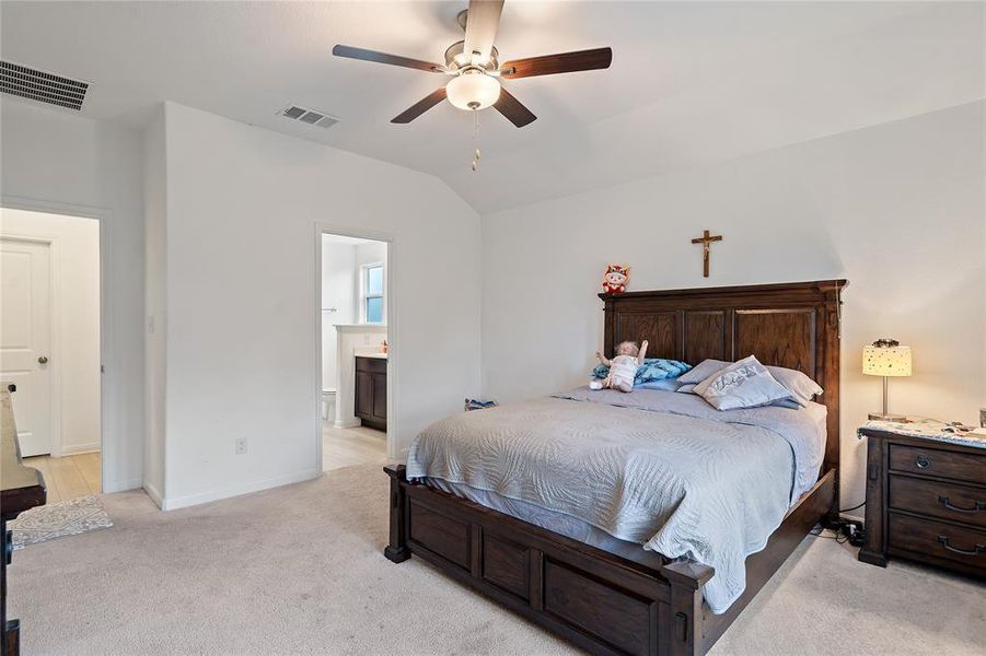 Bedroom featuring light colored carpet, lofted ceiling, a ceiling fan, and ensuite bathroom