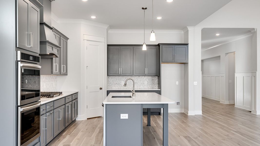 L-shaped Kitchen with corner pantry with gray cabinets and modern style with tile backsplash and range hood