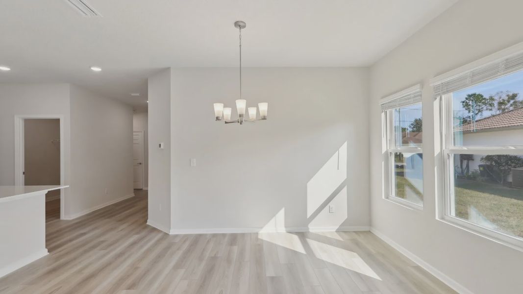 Elegant dining space features sleek wood flooring and a contemporary chandelier, flooding in natural light in Palm Coast.