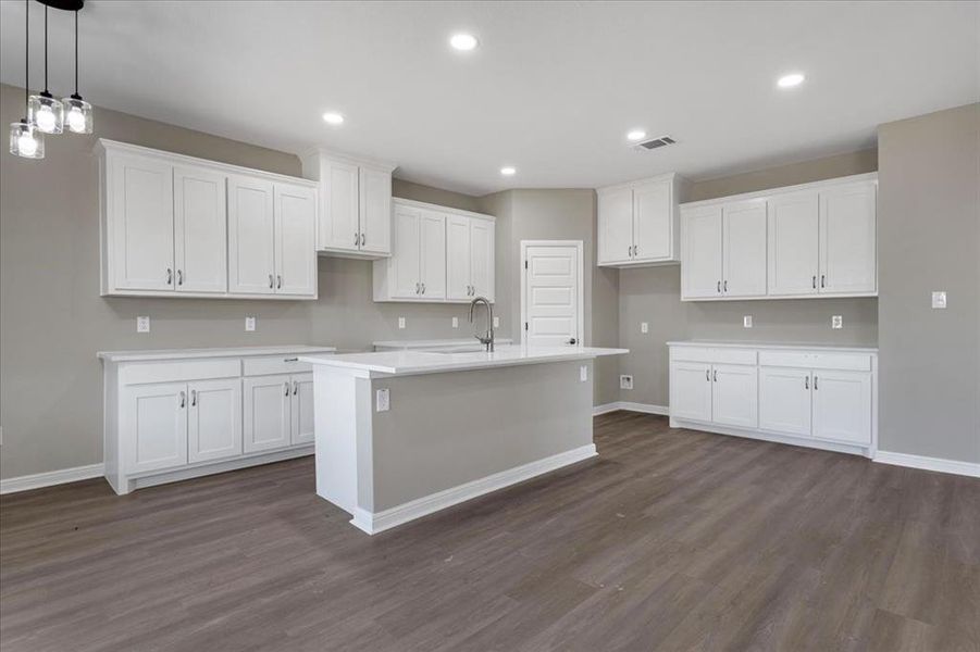 Kitchen featuring white cabinetry, recessed lighting, a kitchen island with sink, dark wood finished floors, and hanging light fixtures