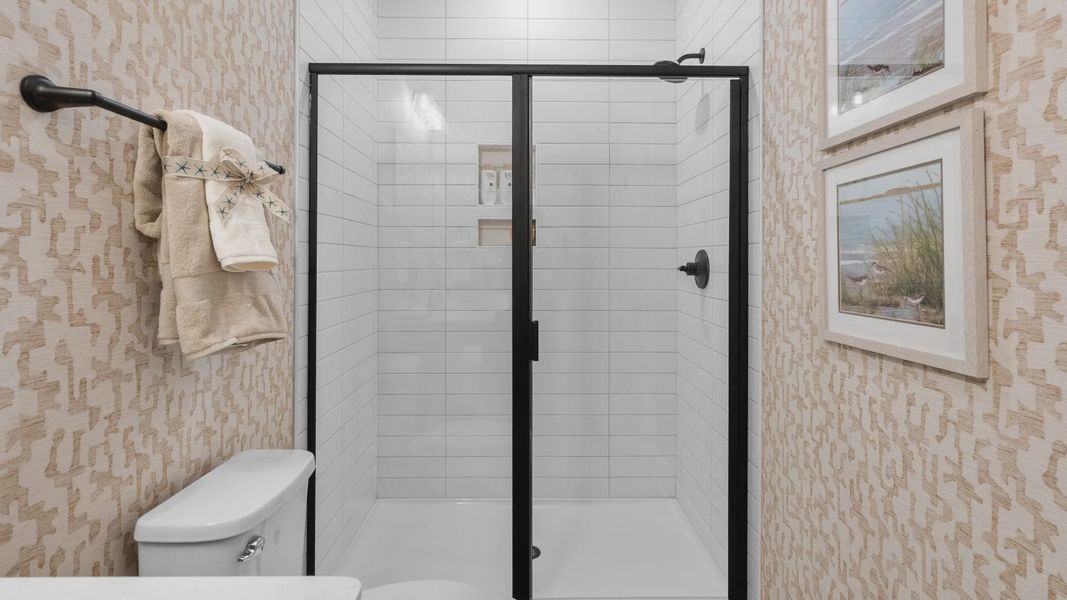 Secondary bathroom shower in the Summit home plan with stylish tile and elegant finishes.