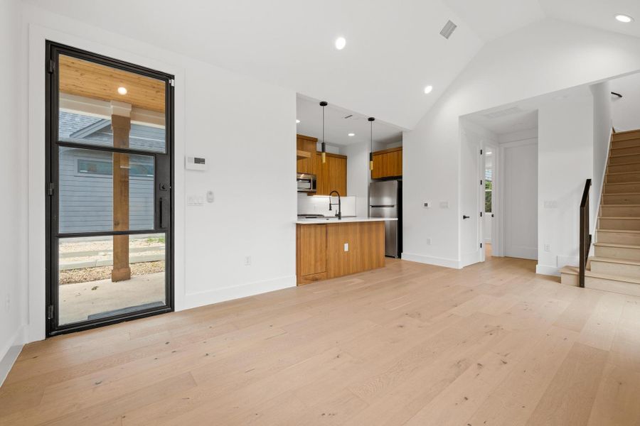 Unfurnished living room with stairway, recessed lighting, light wood-type flooring, and lofted ceiling Unfurnished living room with stairway, recessed lighting, light wood-type flooring, and lofted ceiling