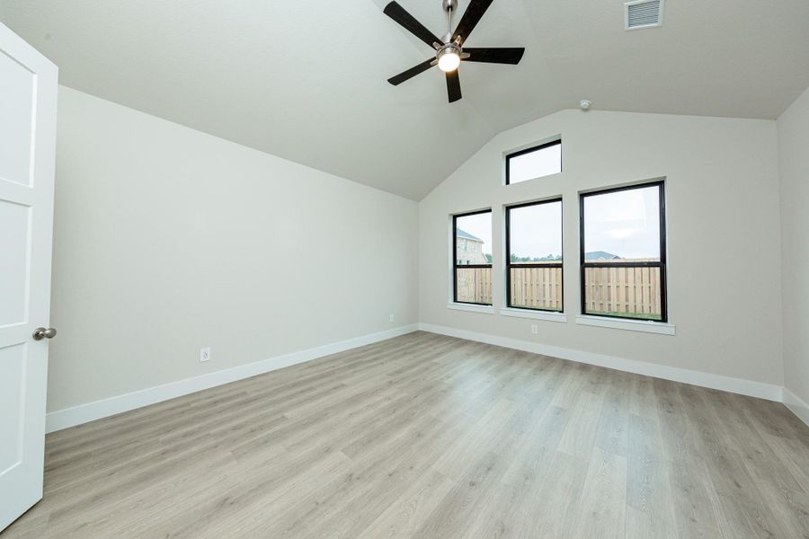 Relax and unwind after a long day in this impressive primary suite! This generously sized room offers laminate flooring, neutral-toned paint, high ceilings with a ceiling fan, and large windows for added comfort and tranquility.