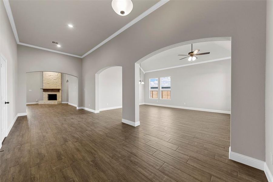 Unfurnished living room with crown molding, dark hardwood / wood-style floors, a fireplace, and ceiling fan