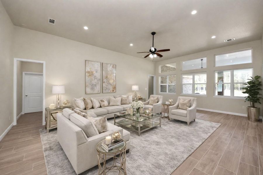 Spacious living room featuring large windows for natural light, and elegant virtually staged furnishings. It includes a ceiling fan, high ceilings, and recessed lighting.