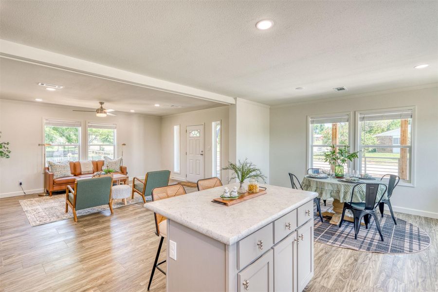 An inviting open-concept layout connects the kitchen, dining area, and living room with seamless wood-look flooring. An inviting open-concept layout connects the kitchen, dining area, and living room with seamless wood-look flooring.